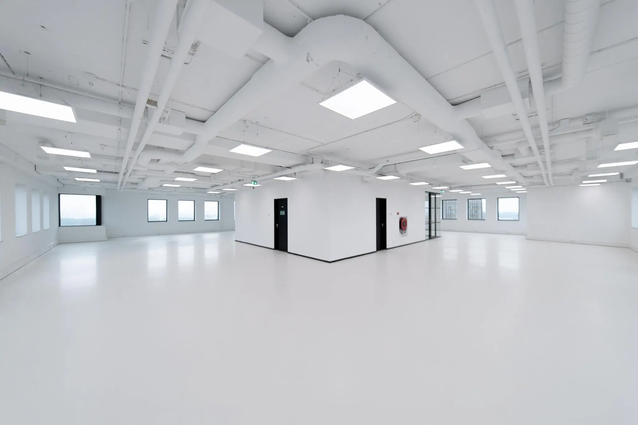 Licht en modern leeg kantoorpand in Rivium Quadrant met witte vloeren, plafonds en zichtbare leidingen.